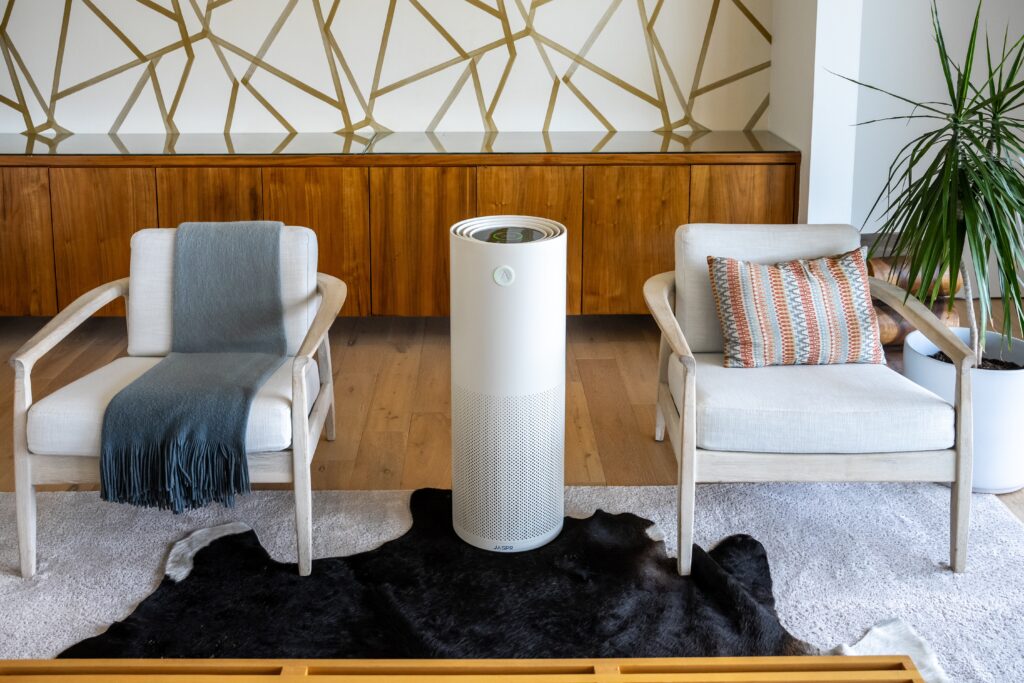 AJaspr air filter in a living room between two arm chairs